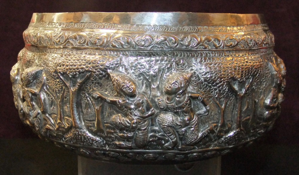 A 19th-century Burmese footed silver bowl featuring high-relief repousse decoration depicting figures, animals, and trees. View IV