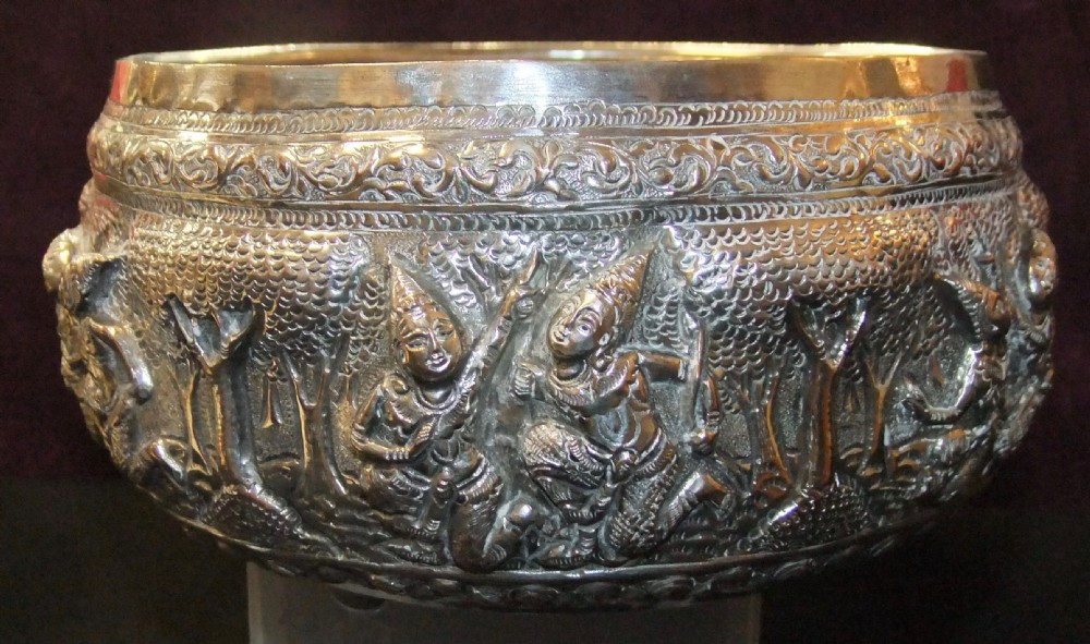 A 19th-century Burmese footed silver bowl featuring high-relief repousse decoration depicting figures, animals, and trees. View V