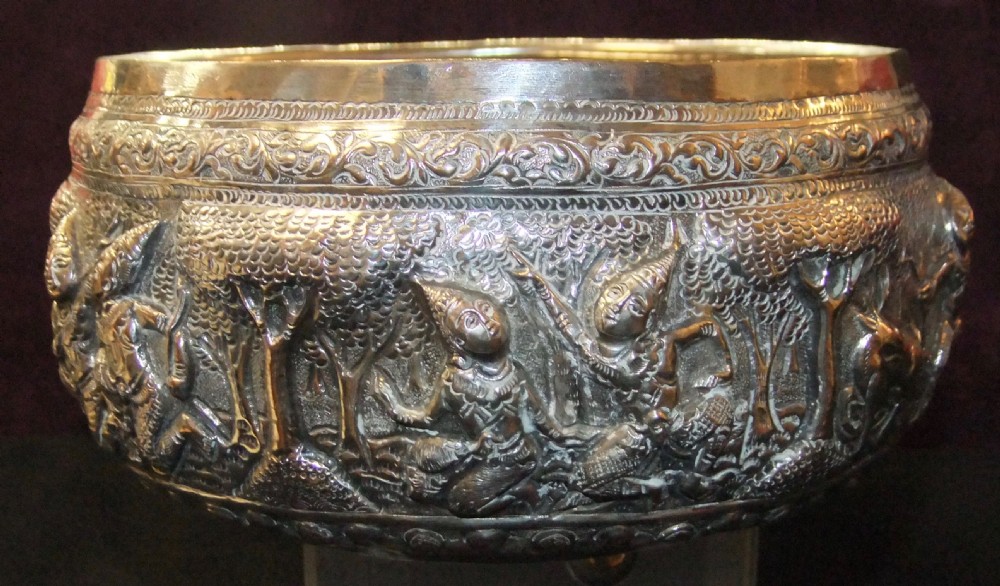 A 19th-century Burmese footed silver bowl featuring high-relief repousse decoration depicting figures, animals, and trees. View VI