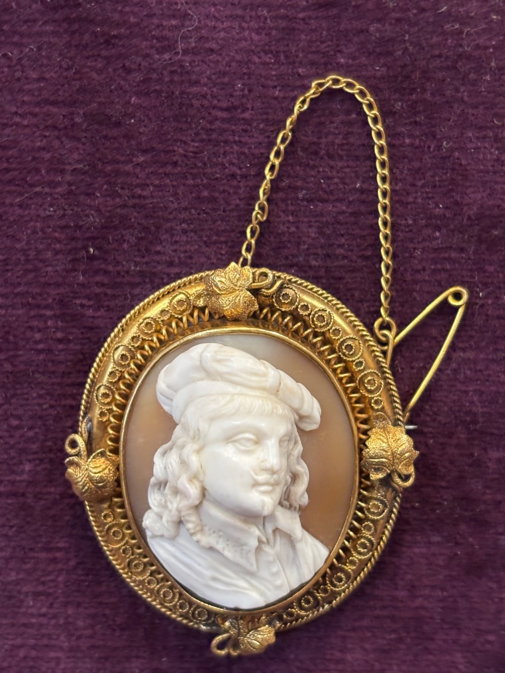 An oval early Victorian shell cameo featuring a carved relief portrait of Bonnie Prince Charlie within an intricate gold filigree border and safety chain.