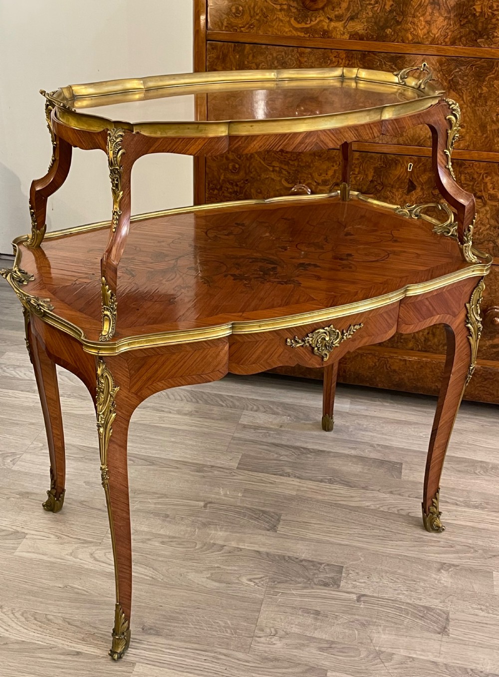 A late 19th-century French kingwood two-tier etagere table with gilt-bronze mounts, floral marquetry, and a glass-bottomed upper tray.