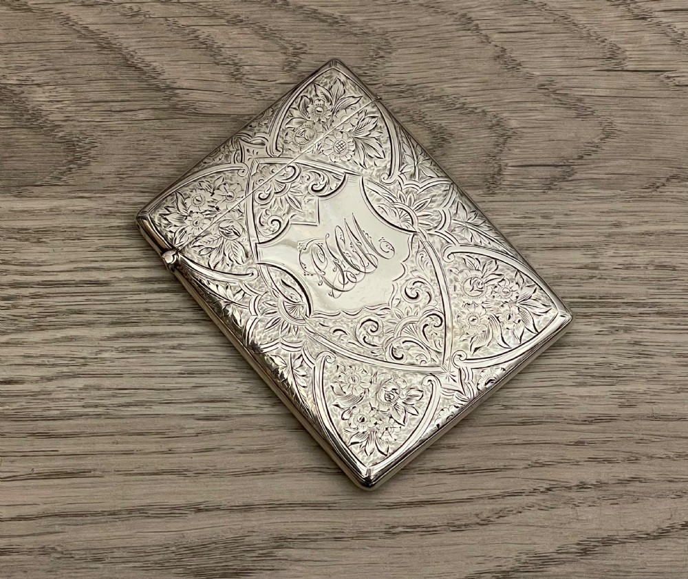 An Edwardian sterling silver calling card case featuring detailed foliate floral engraving and a central monogram cartouche. View II