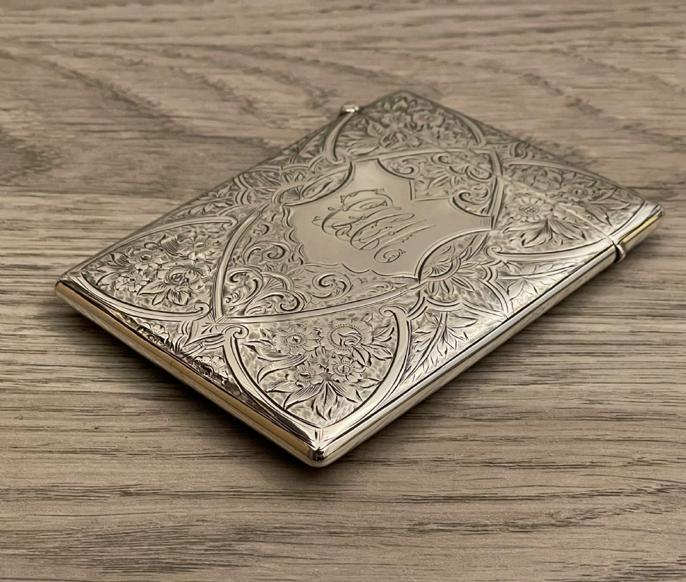 An Edwardian sterling silver calling card case featuring detailed foliate floral engraving and a central monogram cartouche. View V