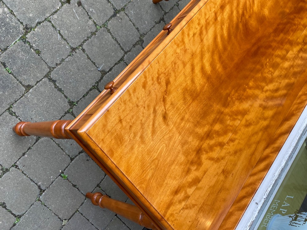 A Victorian satin birch side table featuring a low rear gallery, two front drawers with turned wooden knobs, and four turned tapered legs. View V