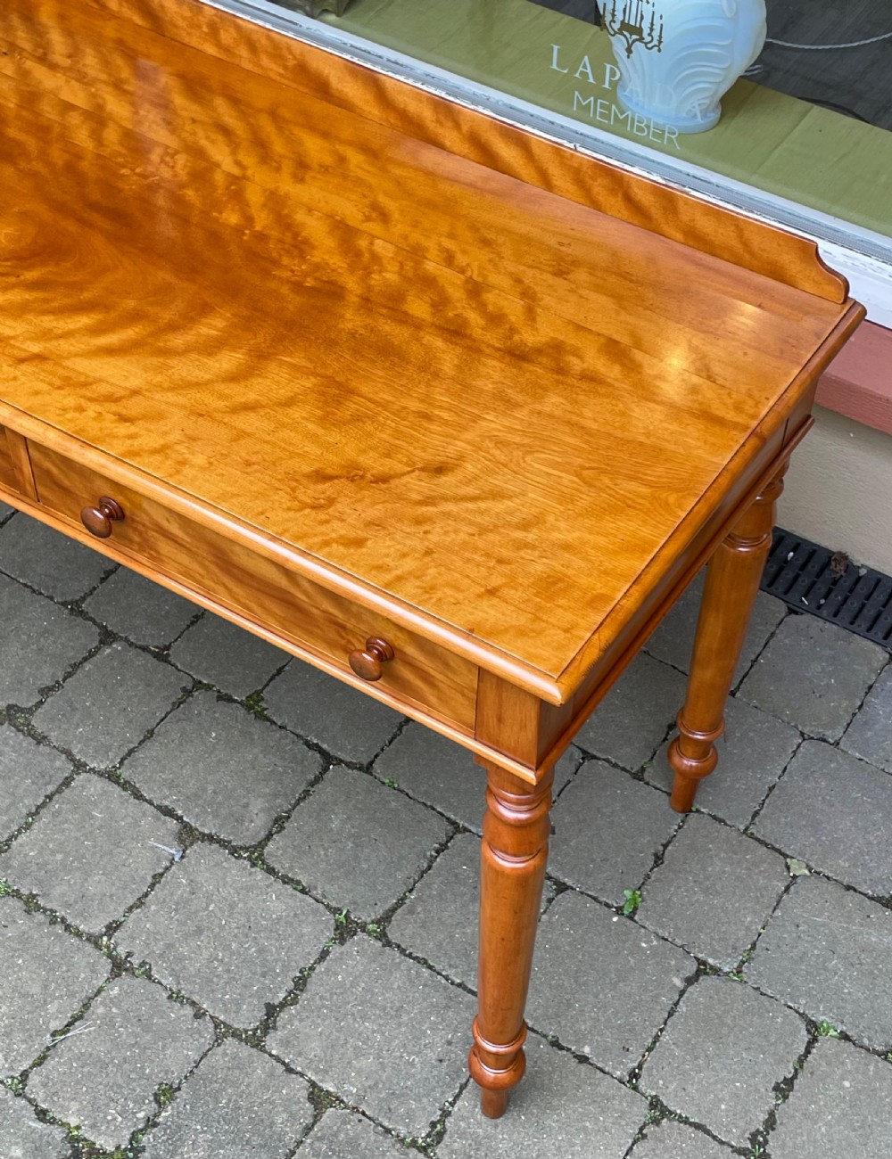 A Victorian satin birch side table featuring a low rear gallery, two front drawers with turned wooden knobs, and four turned tapered legs. View VI