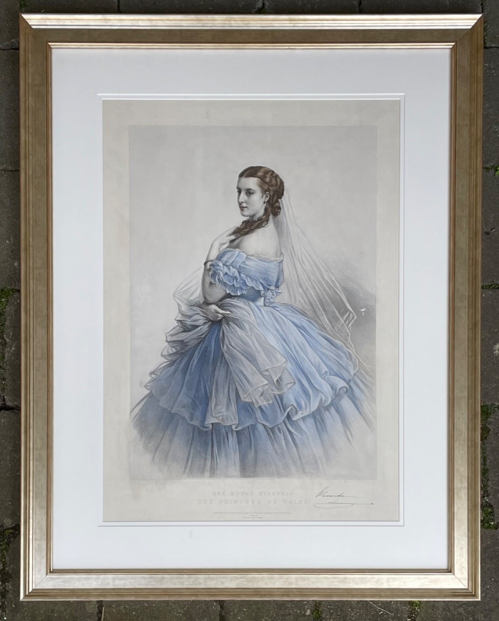 A framed 19th-century portrait lithograph of Princess Alexandra wearing a layered blue gown and white veil, presented in a gilded frame with a light mount.