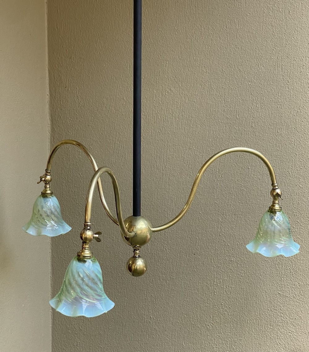 An Arts and Crafts brass ceiling light featuring three curved arms holding pale green frilled glass shades on a central drop rod. View II