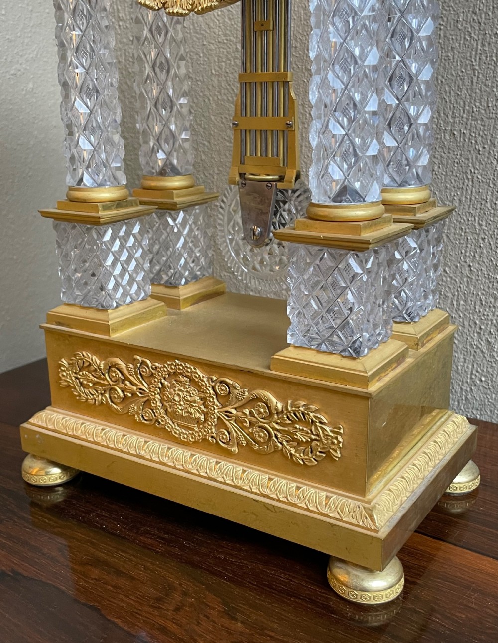 A French Charles X portico mantel clock designed with four diamond-cut crystal columns, gilt ormolu mounts, an engine-turned circular dial, and a pendulum. View II