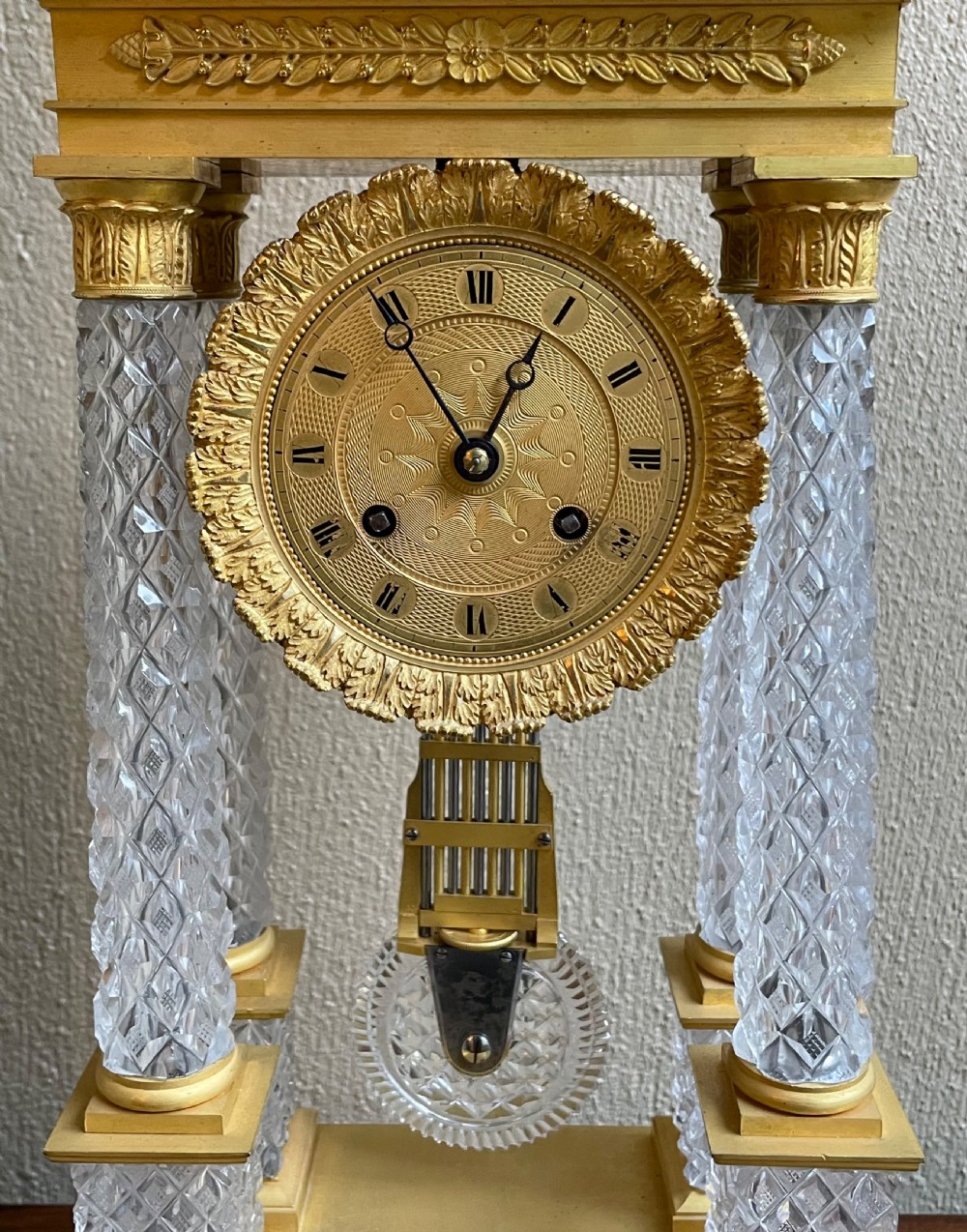 A French Charles X portico mantel clock designed with four diamond-cut crystal columns, gilt ormolu mounts, an engine-turned circular dial, and a pendulum. View III