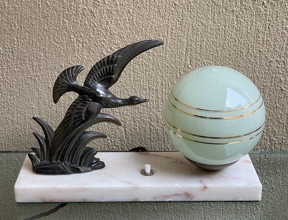 A French Art Deco table lamp featuring a dark patinated spelter bird figure and a frosted green glass globe shade mounted on a rectangular pink marble base. View II