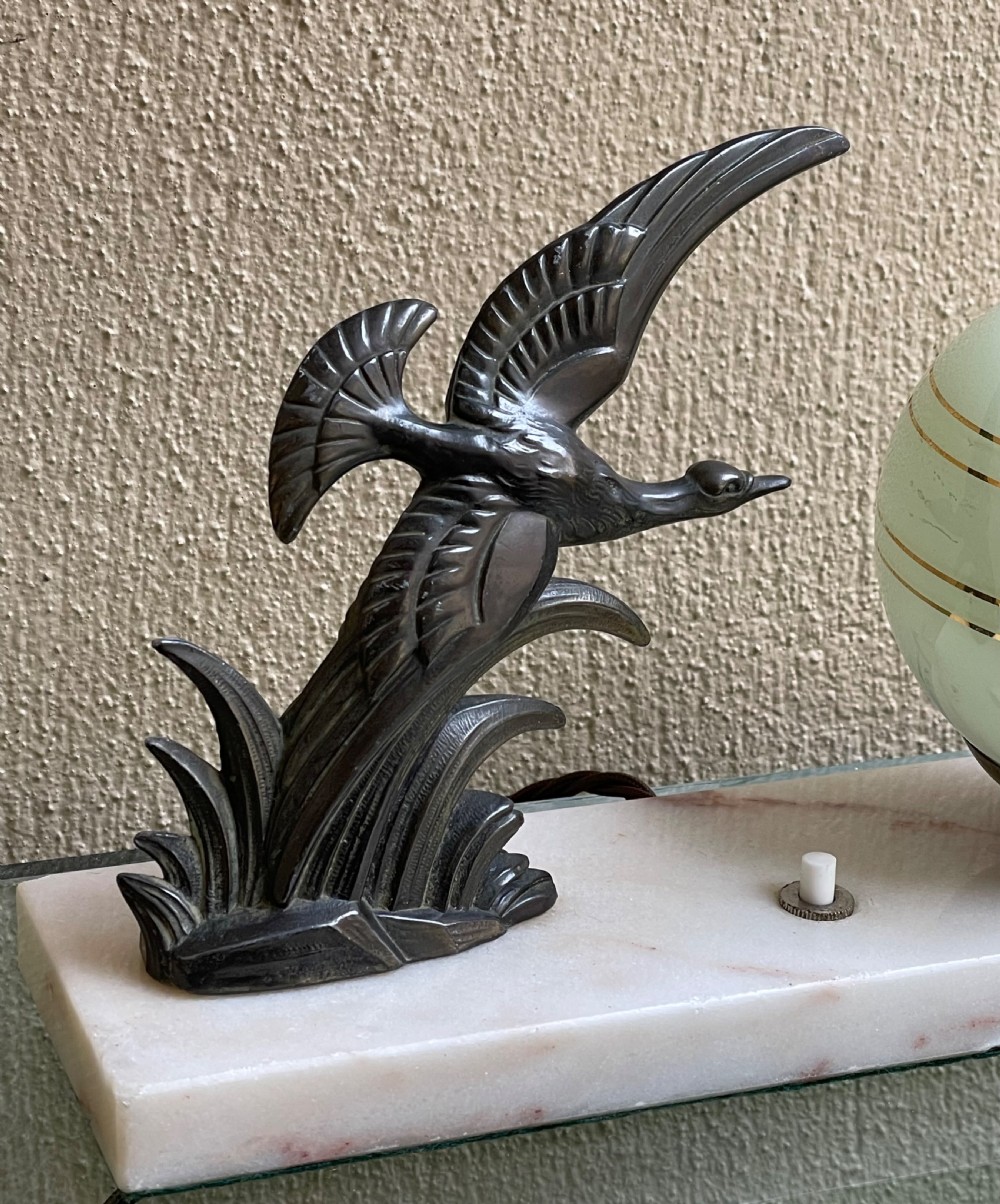 A French Art Deco table lamp featuring a dark patinated spelter bird figure and a frosted green glass globe shade mounted on a rectangular pink marble base. View IV