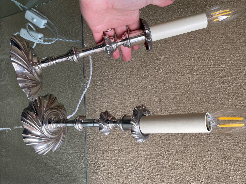 A pair of Victorian silver-plated electric candlestick lamps featuring swirl fluted bases and shafts fitted with cream candle sleeves. View III