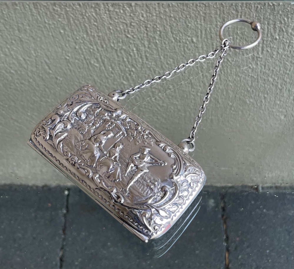 A sterling silver ladies purse featuring embossed repousse architectural scenery, a push-button catch, and a fine chain handle with a finger ring. View II