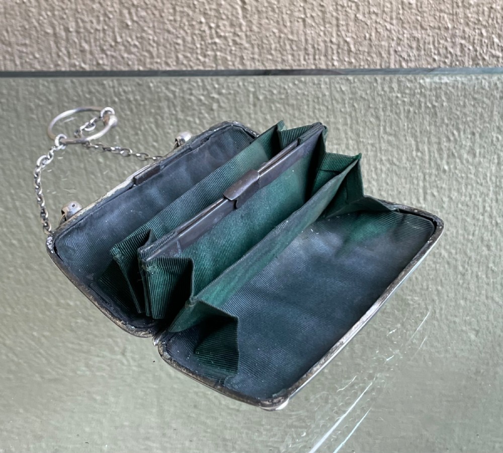 A sterling silver ladies purse featuring embossed repousse architectural scenery, a push-button catch, and a fine chain handle with a finger ring. View V