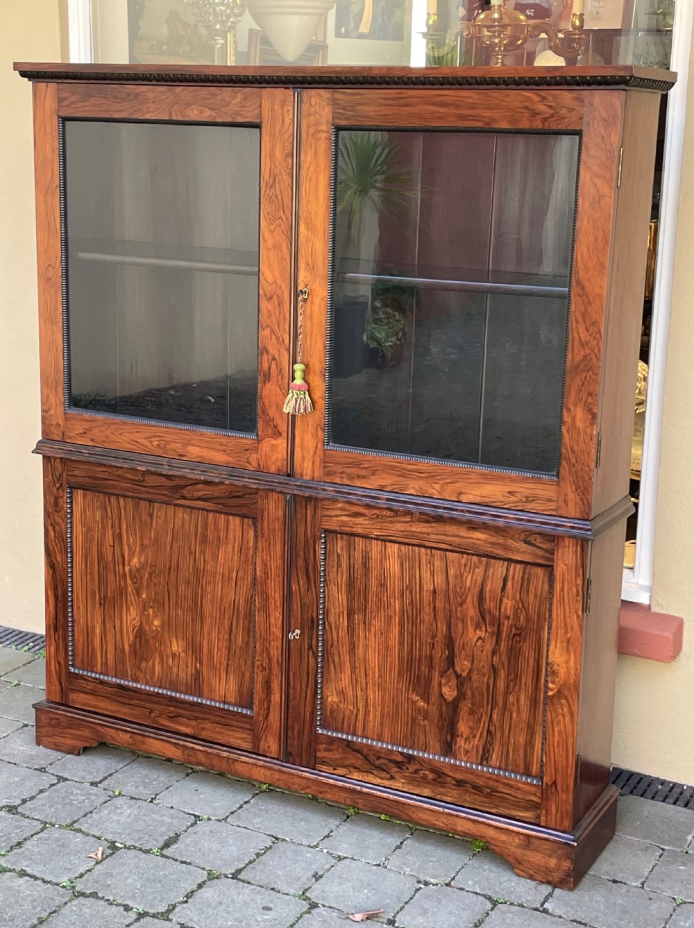 Nineteenth-century two-tier rosewood cabinet with upper glazed double doors and lower solid panel doors framed by beaded trim.