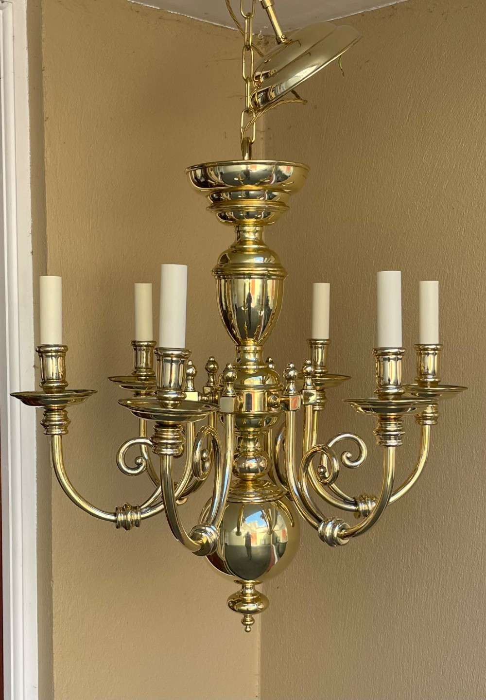 A polished brass six-arm chandelier featuring a turned central baluster stem, curved S-scrolled arms with candle sleeves, and a ceiling chain suspension. View II
