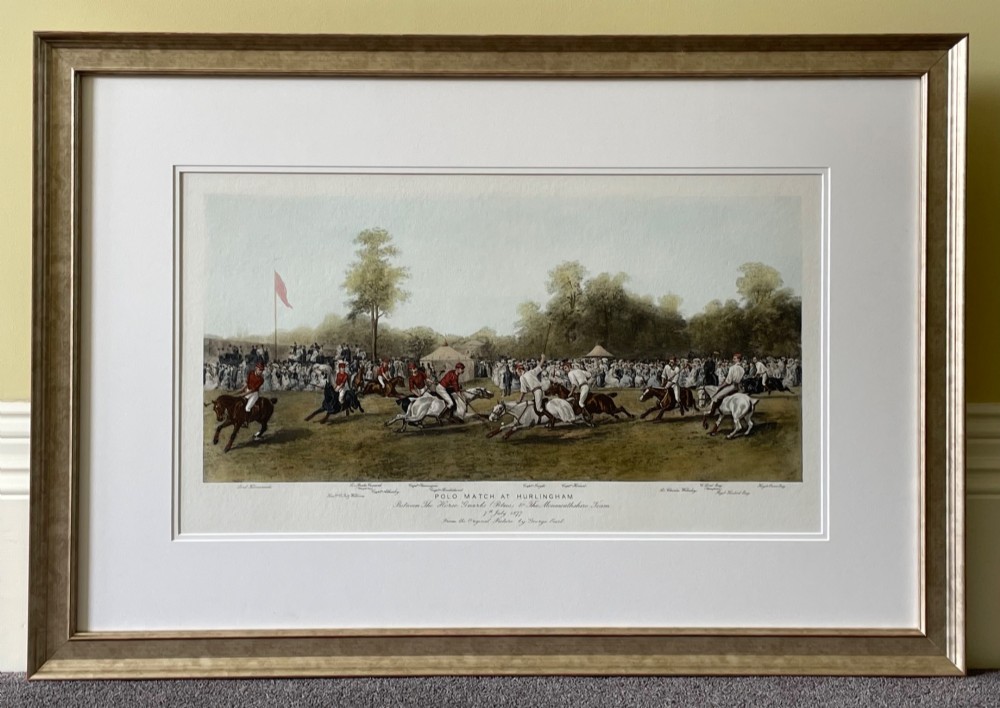 A framed nineteenth-century coloured lithograph depicting a polo match at Hurlingham with riders on horseback and spectators surrounding a green field, presented in a double mount and metallic frame.