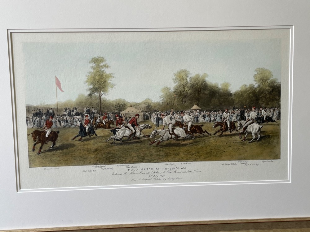 A framed nineteenth-century coloured lithograph depicting a polo match at Hurlingham with riders on horseback and spectators surrounding a green field, presented in a double mount and metallic frame. View II