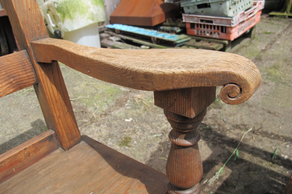 A long Victorian wooden waiting room bench featuring turned front legs, sculpted armrests, and an open rail back. View II