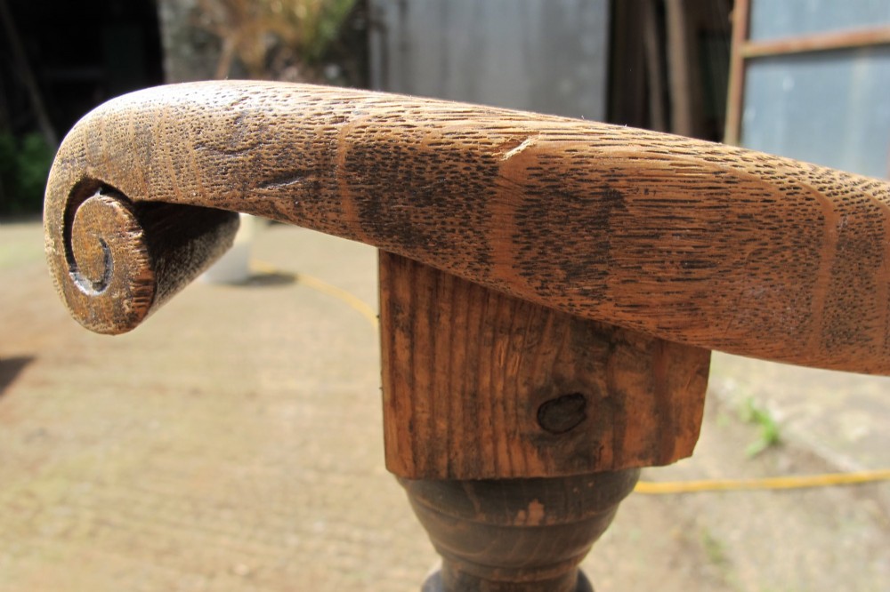 A long Victorian wooden waiting room bench featuring turned front legs, sculpted armrests, and an open rail back. View IV