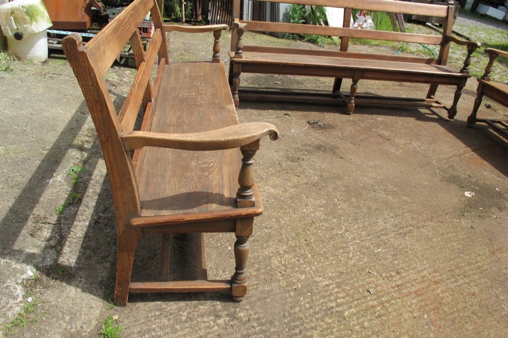 A long Victorian wooden waiting room bench featuring turned front legs, sculpted armrests, and an open rail back. View IX