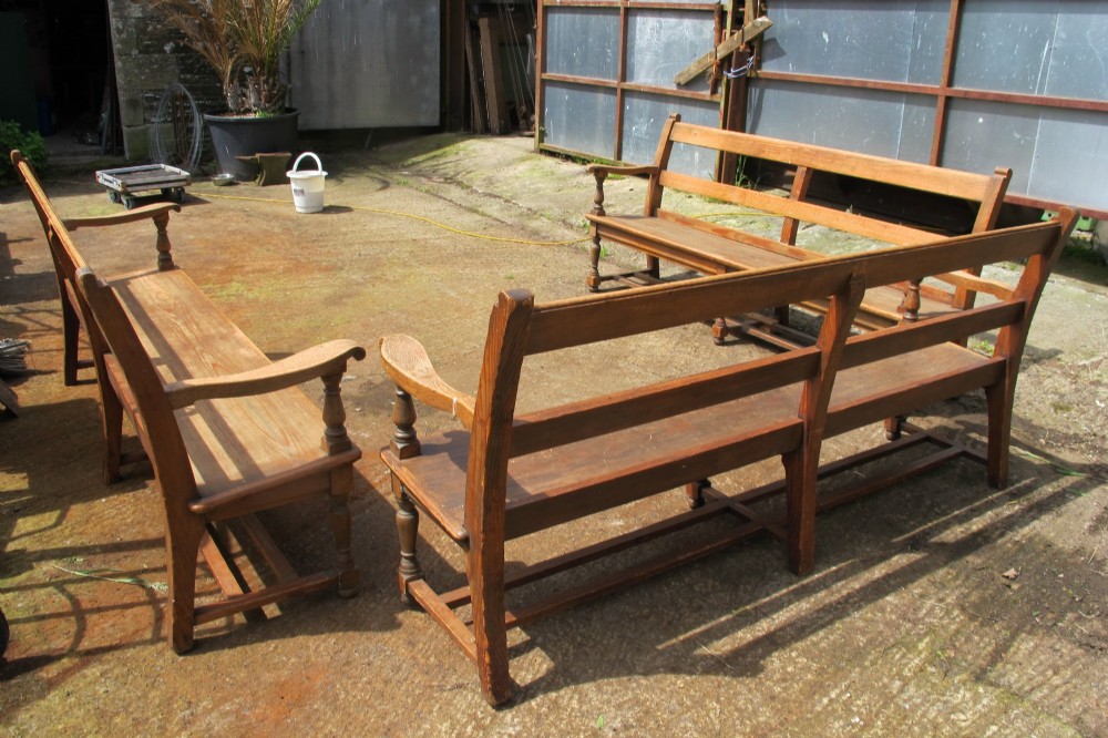 A long Victorian wooden waiting room bench featuring turned front legs, sculpted armrests, and an open rail back. View XI