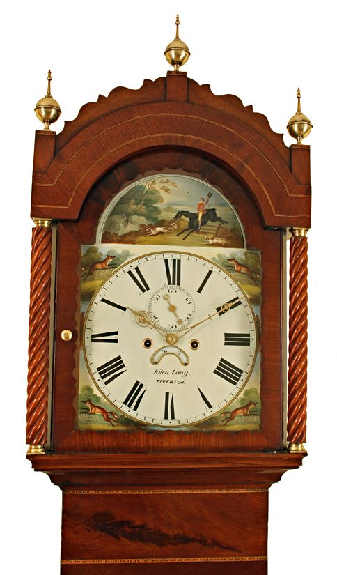 fig 1. An antique Georgian mahogany longcase clock featuring brass finials, spiral-twist column details, and a painted dial depicting an equestrian hunting scene.