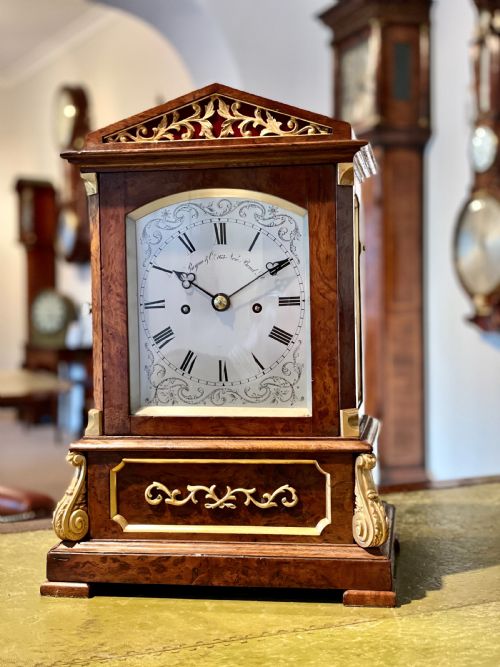fig 1. A Victorian pollard oak bracket clock featuring an engraved white dial, Roman numerals, and gilt scrollwork accents.