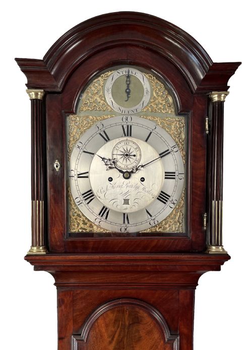 fig 1. A Georgian dark flame mahogany longcase clock featuring an arched hood with reeded brass-capped columns and an engraved brass dial.