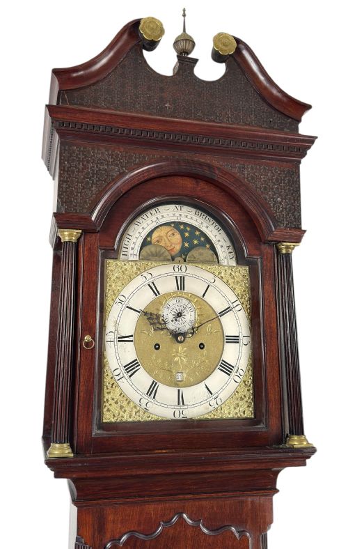 fig 1. A Georgian mahogany longcase clock featuring a swan-neck pediment, fluted side columns, and an arched brass dial with a painted moonphase display.