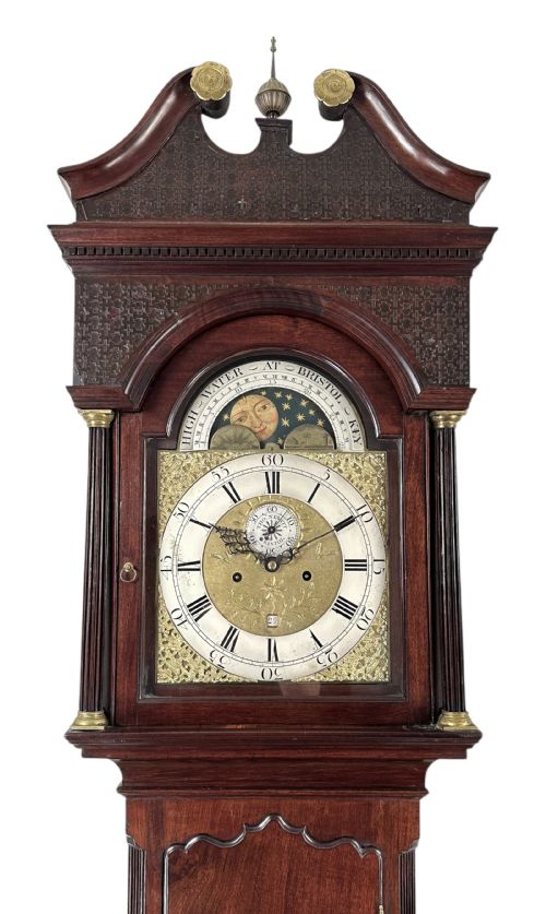fig 2. A Georgian mahogany longcase clock featuring a swan-neck pediment, fluted side columns, and an arched brass dial with a painted moonphase display.