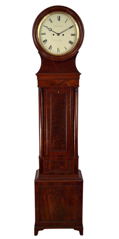 fig 3. A Scottish Regency flame mahogany longcase clock featuring a circular brass-rimmed dial with Roman numerals and a veneered trunk on bracket feet.