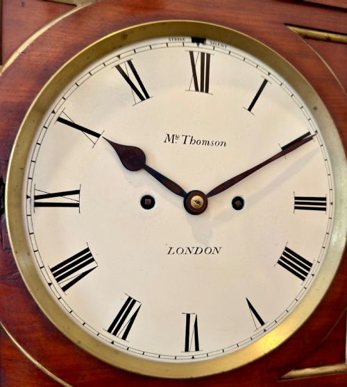 fig 2. A Regency mahogany bracket clock featuring a cream dial with Roman numerals signed Thomson London, set within a brass-inlaid wooden case.