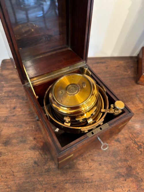 fig 3. A Thomas Mercer marine chronometer with a silvered dial and brass gimbal mechanism set inside an open mahogany box.