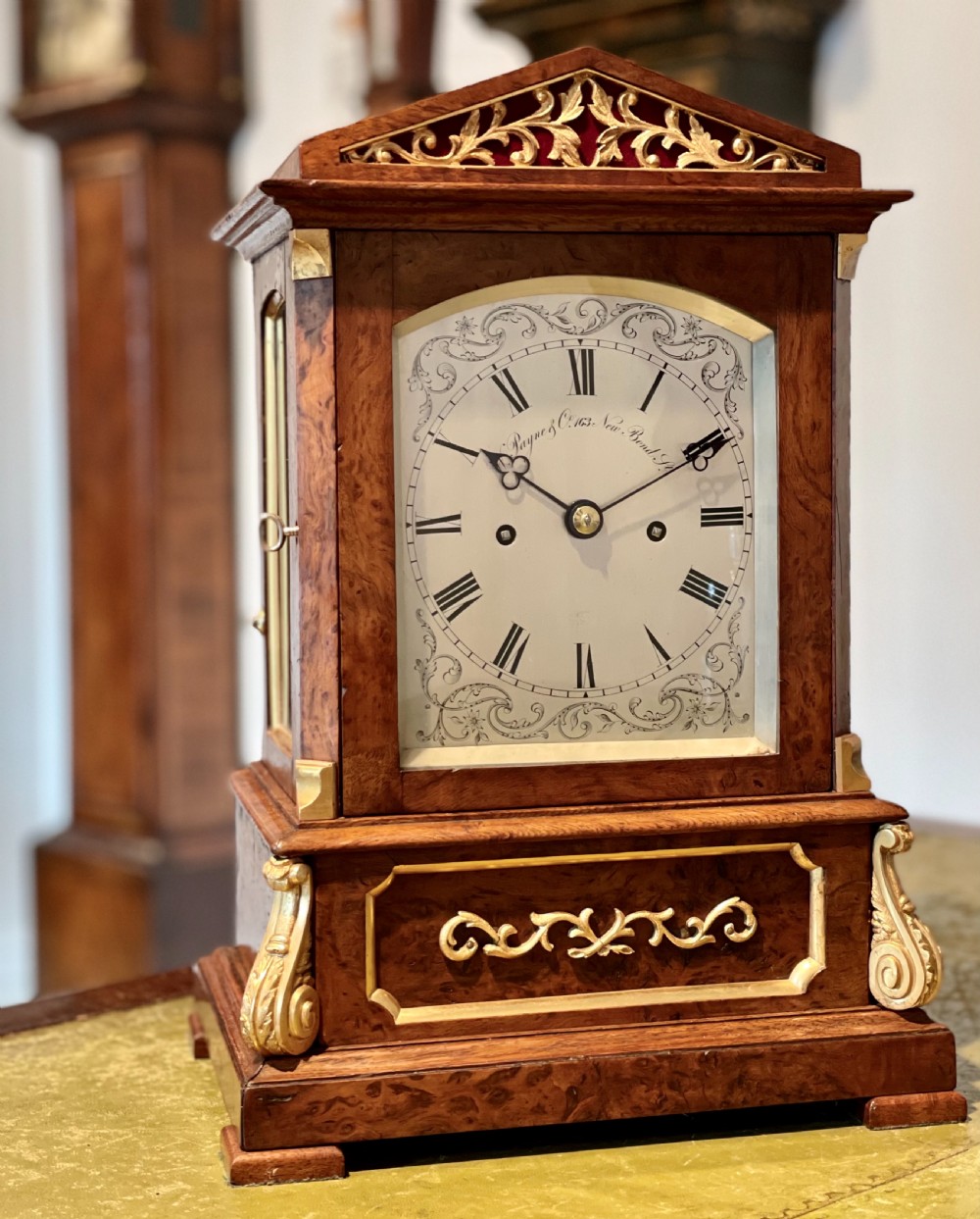 A Victorian pollard oak bracket clock featuring an engraved white dial, Roman numerals, and gilt scrollwork accents.