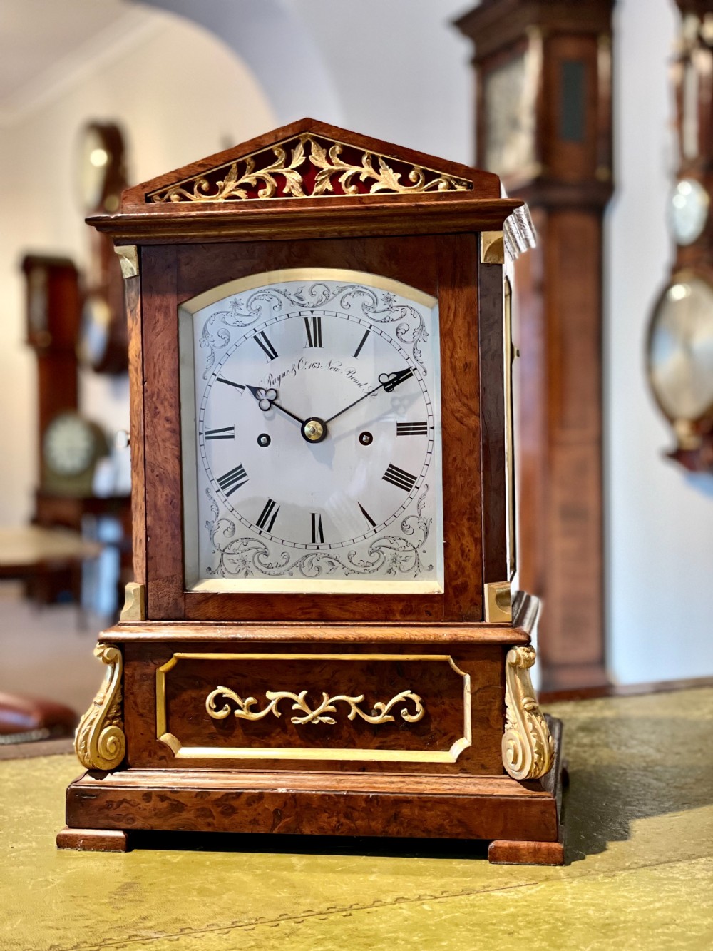 A Victorian pollard oak bracket clock featuring an engraved white dial, Roman numerals, and gilt scrollwork accents. View II