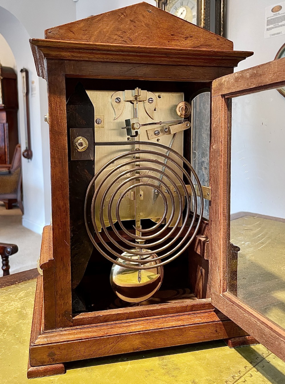 A Victorian pollard oak bracket clock featuring an engraved white dial, Roman numerals, and gilt scrollwork accents. View IV