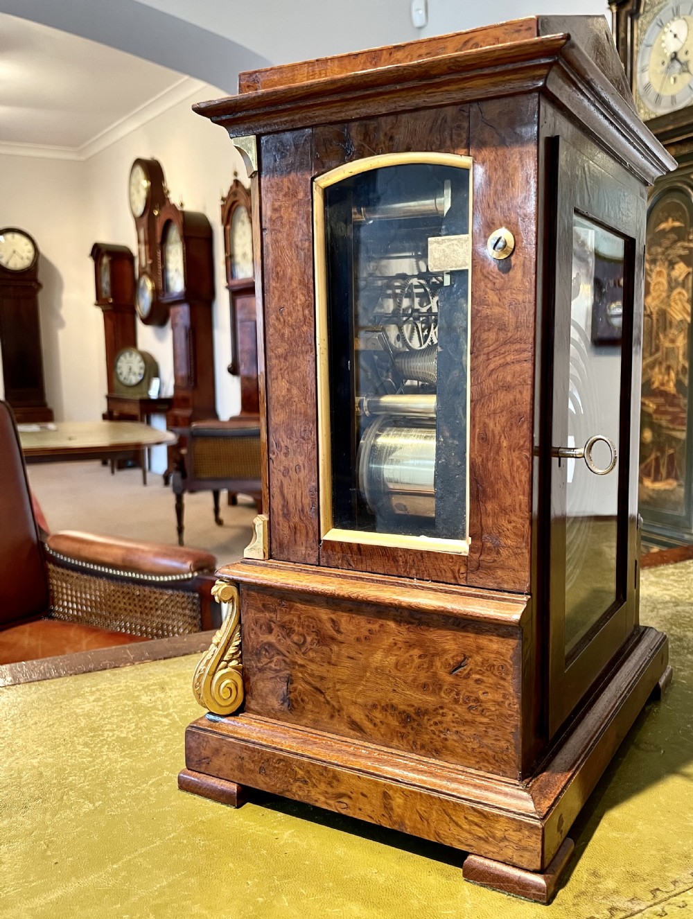 A Victorian pollard oak bracket clock featuring an engraved white dial, Roman numerals, and gilt scrollwork accents. View VI