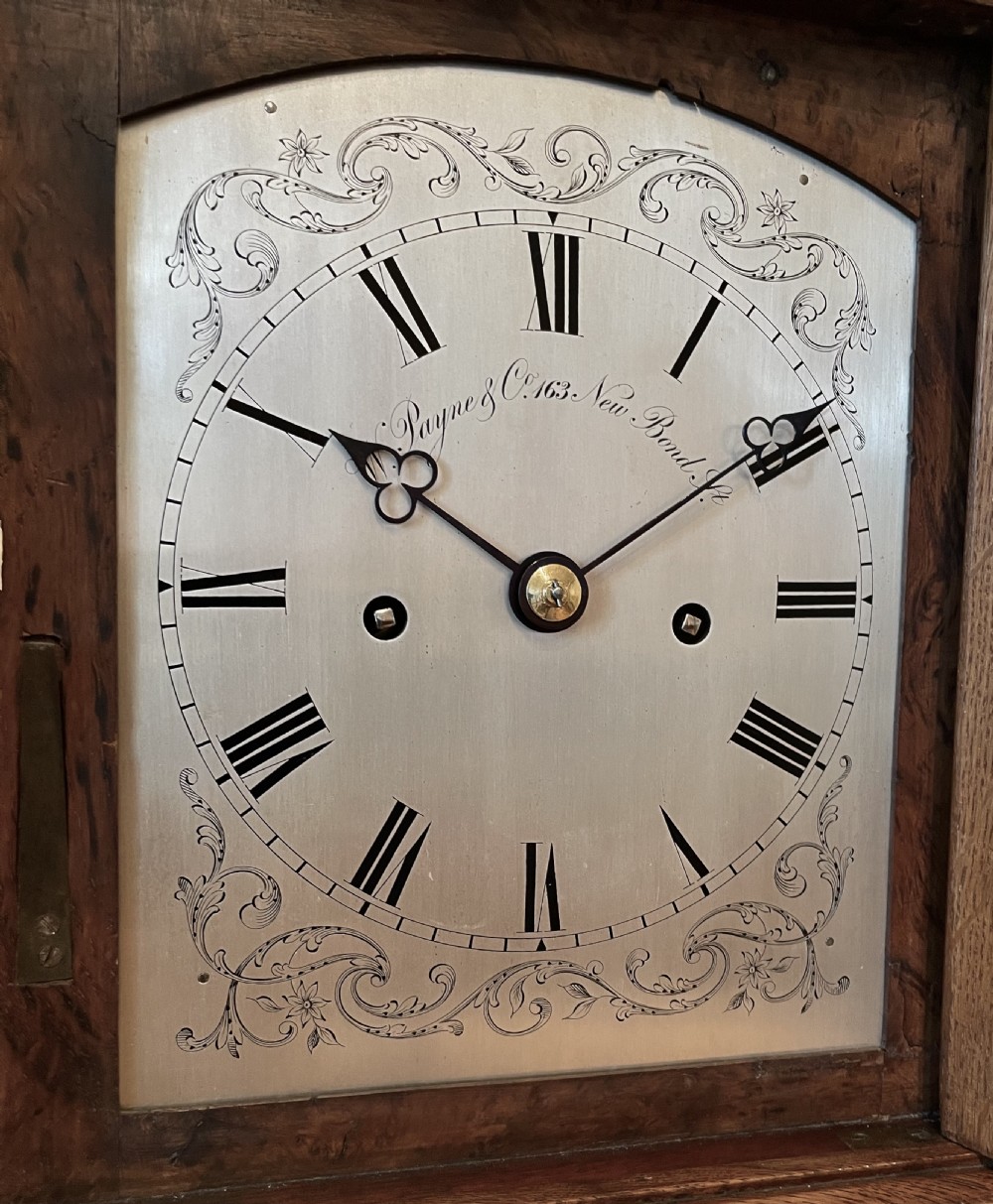 A Victorian pollard oak bracket clock featuring an engraved white dial, Roman numerals, and gilt scrollwork accents. View VIII