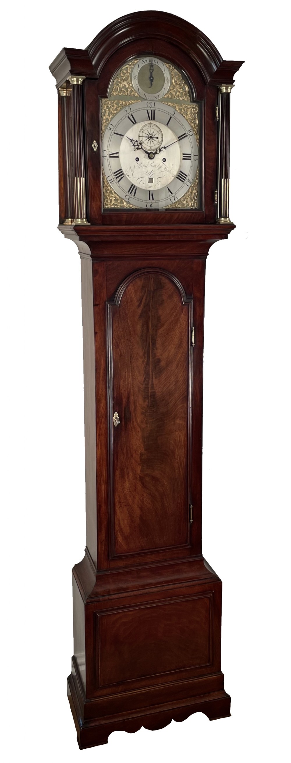 A Georgian dark flame mahogany longcase clock featuring an arched hood with reeded brass-capped columns and an engraved brass dial.