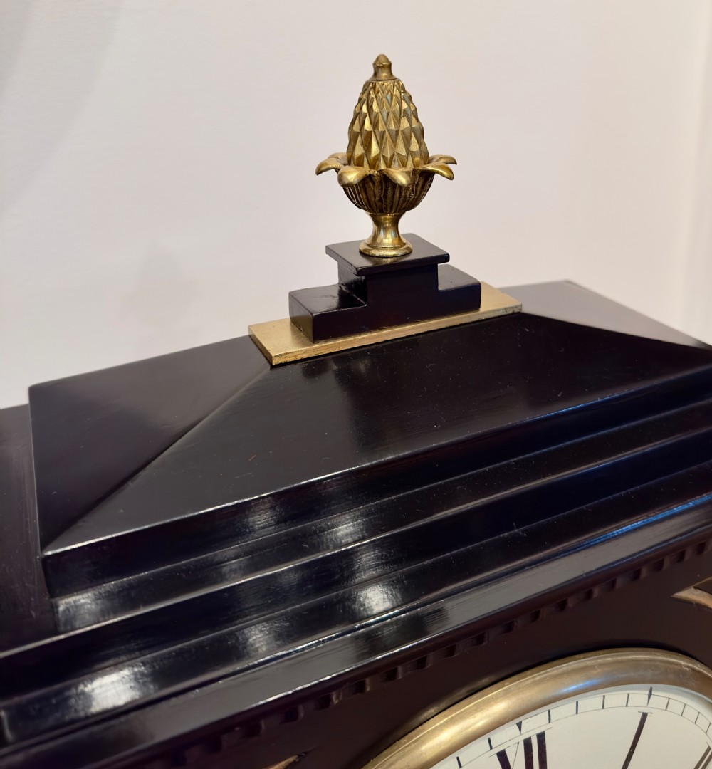 An antique Regency ebonised bracket clock with brass mounts, pineapple finial, ball feet, and a white dial signed J. Berguer Strand London. View III
