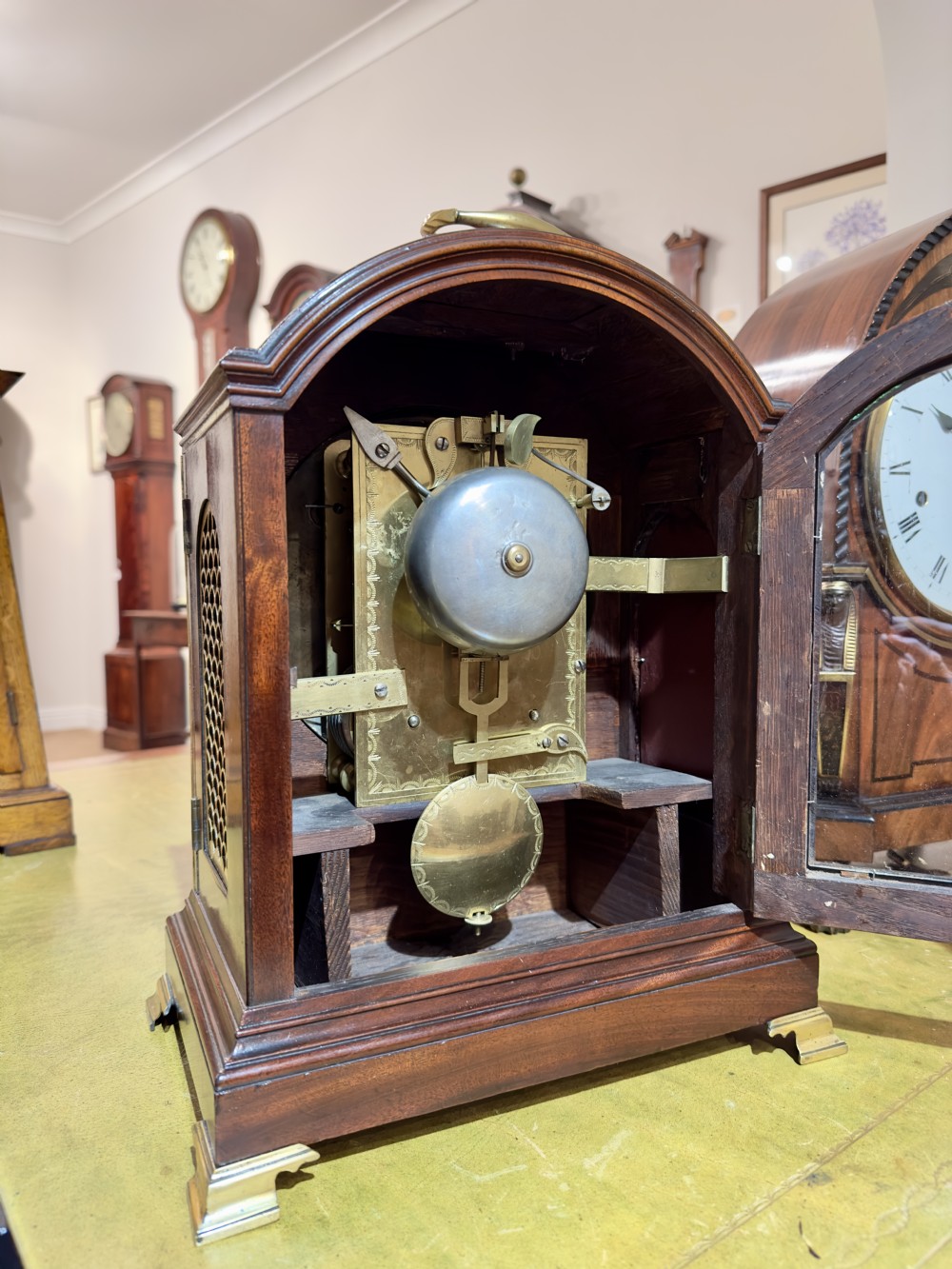 A Regency mahogany bracket clock featuring an arched case, brass carrying handle, circular dial with Roman numerals, and brass bracket feet. View III