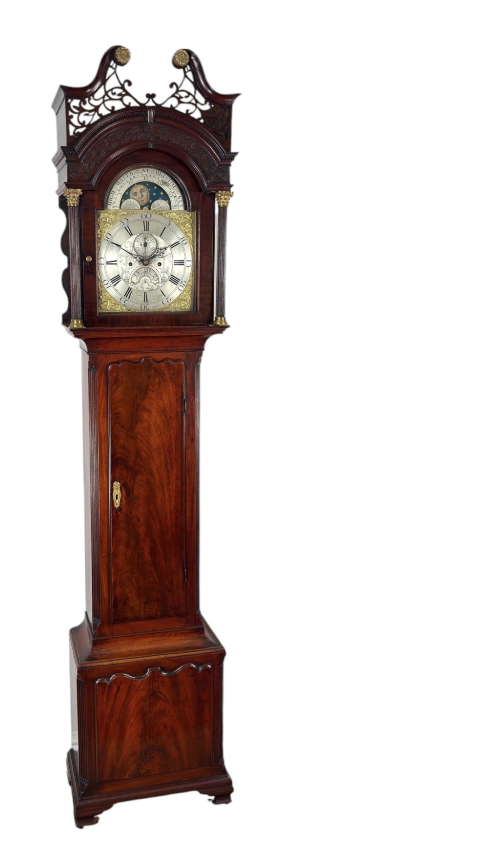 An antique Georgian mahogany longcase clock featuring a swan-neck pediment with pierced fretwork, a moonphase arch dial, and brass-mounted corner columns.