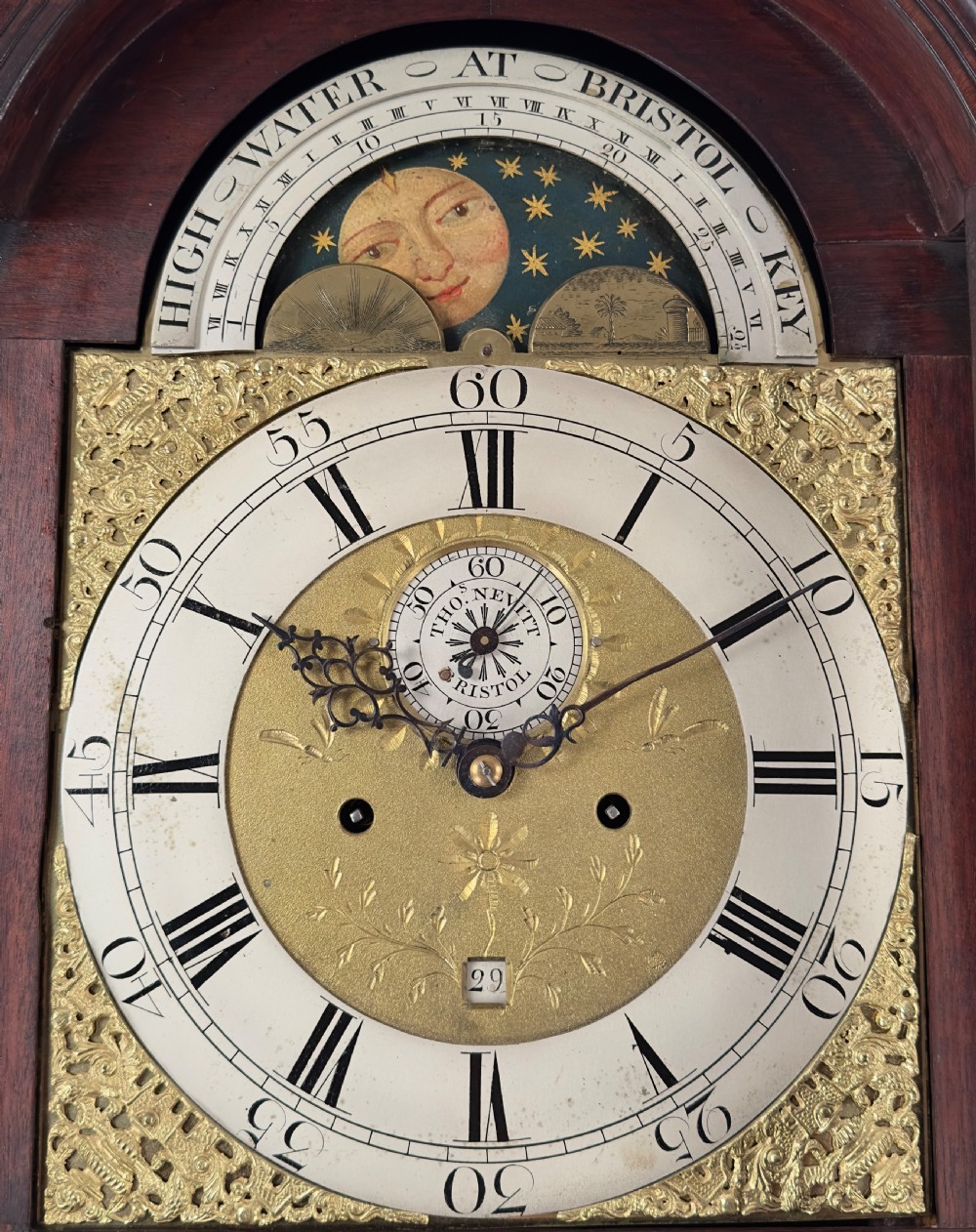 A Georgian mahogany longcase clock featuring a swan-neck pediment, fluted side columns, and an arched brass dial with a painted moonphase display. View V