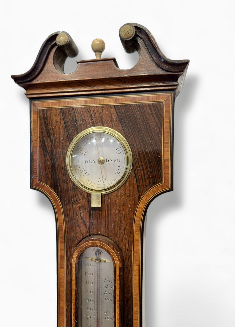 A vertical Regency rosewood banjo clock barometer featuring an inlaid wooden case, top hygrometer, thermometer tube, central clock dial, and large silvered barometer dial. View V