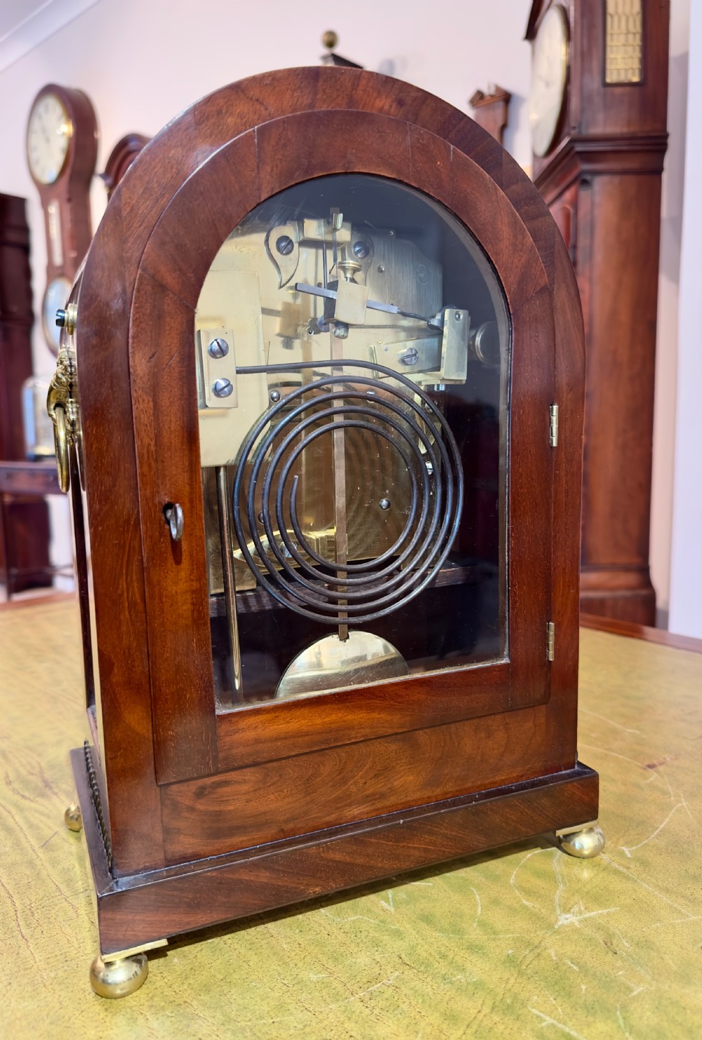 An arched antique mahogany bracket clock with brass scroll inlay, lion-mask ring handles, and a white dial signed Hyde Salisbury. View II