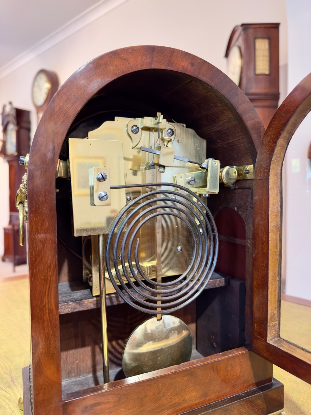 An arched antique mahogany bracket clock with brass scroll inlay, lion-mask ring handles, and a white dial signed Hyde Salisbury. View III