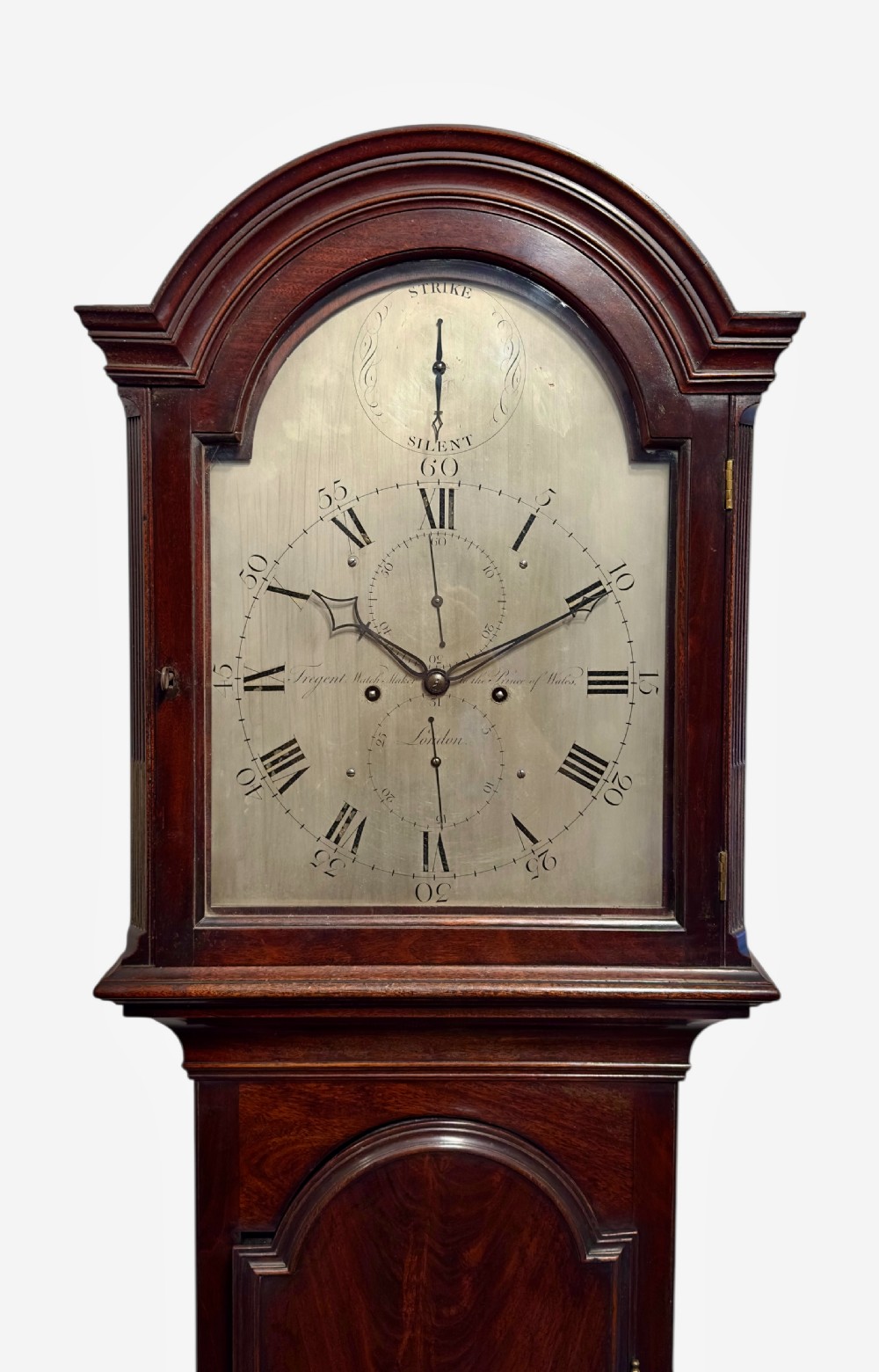 A George III dark mahogany longcase clock featuring an arched hood, silvered dial, and flame mahogany veneered trunk door. View II