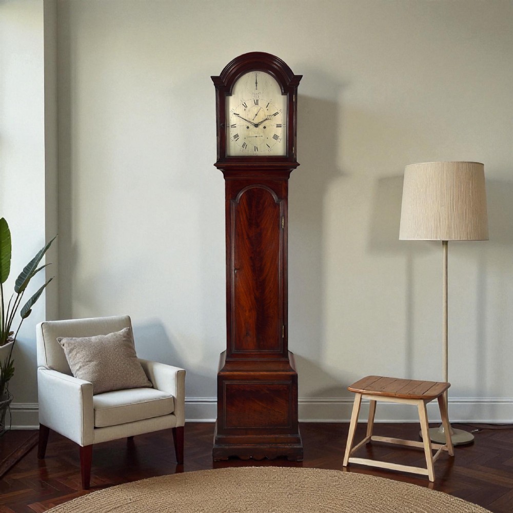 A George III dark mahogany longcase clock featuring an arched hood, silvered dial, and flame mahogany veneered trunk door. View III