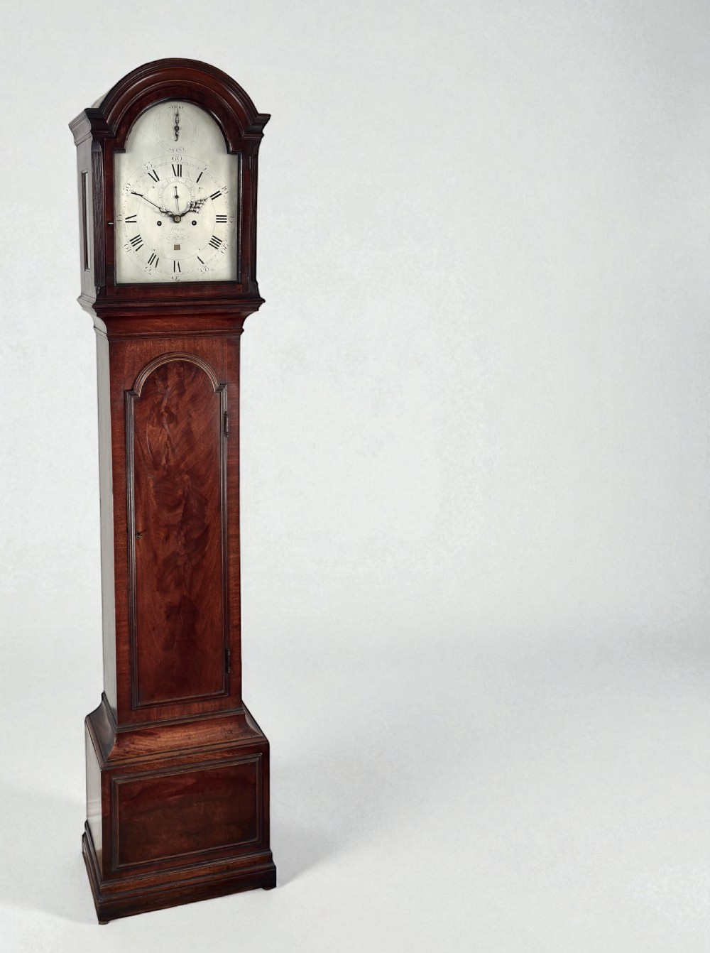 An 18th-century Georgian flame mahogany longcase clock featuring an arched hood, silvered dial with Roman numerals, and a tall wooden trunk.
